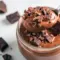 Jar of creamy High Protein Low Carb Snack protein pudding topped with a few nuts and cocoa nibs — a grab-and-go High Protein Low Carb Snack for post-workout or on-the-go fuel.