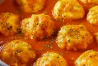 Bowl of Comfort Soups for Cold Weather — creamy tomato broth topped with golden Cheddar Bay dumplings and a sprinkle of parsley, a warm Tomato Dumpling Soup presentation.