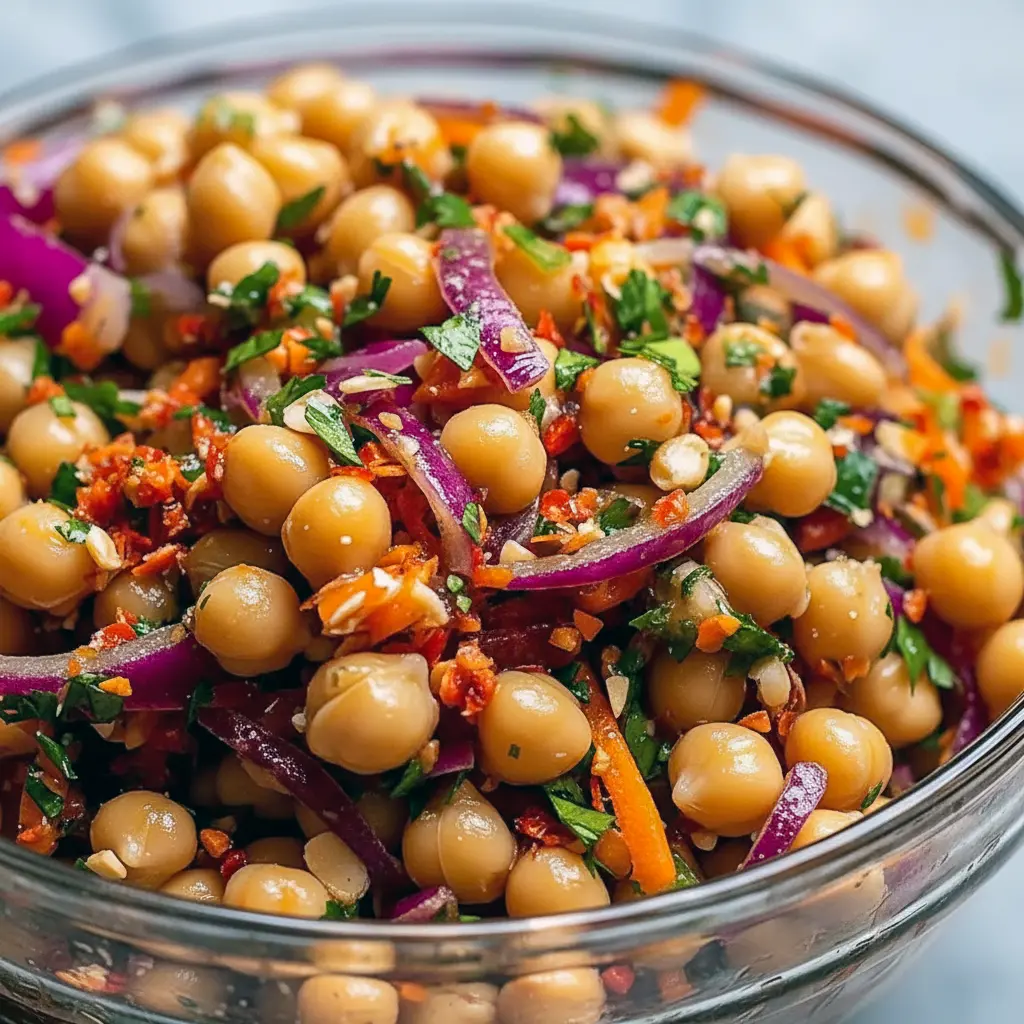 Bowl of Asian Chickpea Salad with shredded red cabbage, diced bell pepper, chickpeas, chopped peanuts, and a creamy tahini-lime dressing.