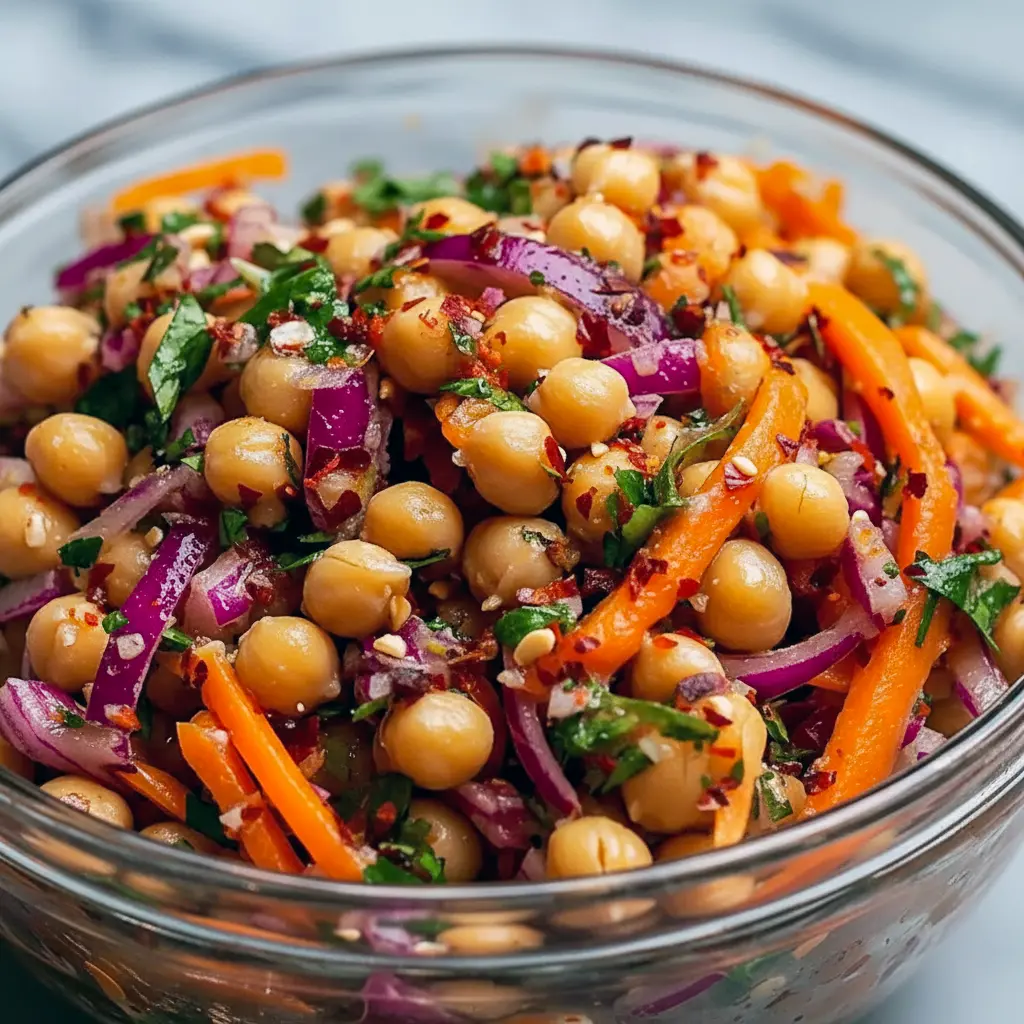 Bowl of Asian Chickpea Salad with shredded red cabbage, diced bell pepper, chickpeas, chopped peanuts, and a creamy tahini-lime dressing.