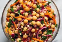 Bowl of Asian Chickpea Salad with shredded red cabbage, diced bell pepper, chickpeas, chopped peanuts, and a creamy tahini-lime dressing.