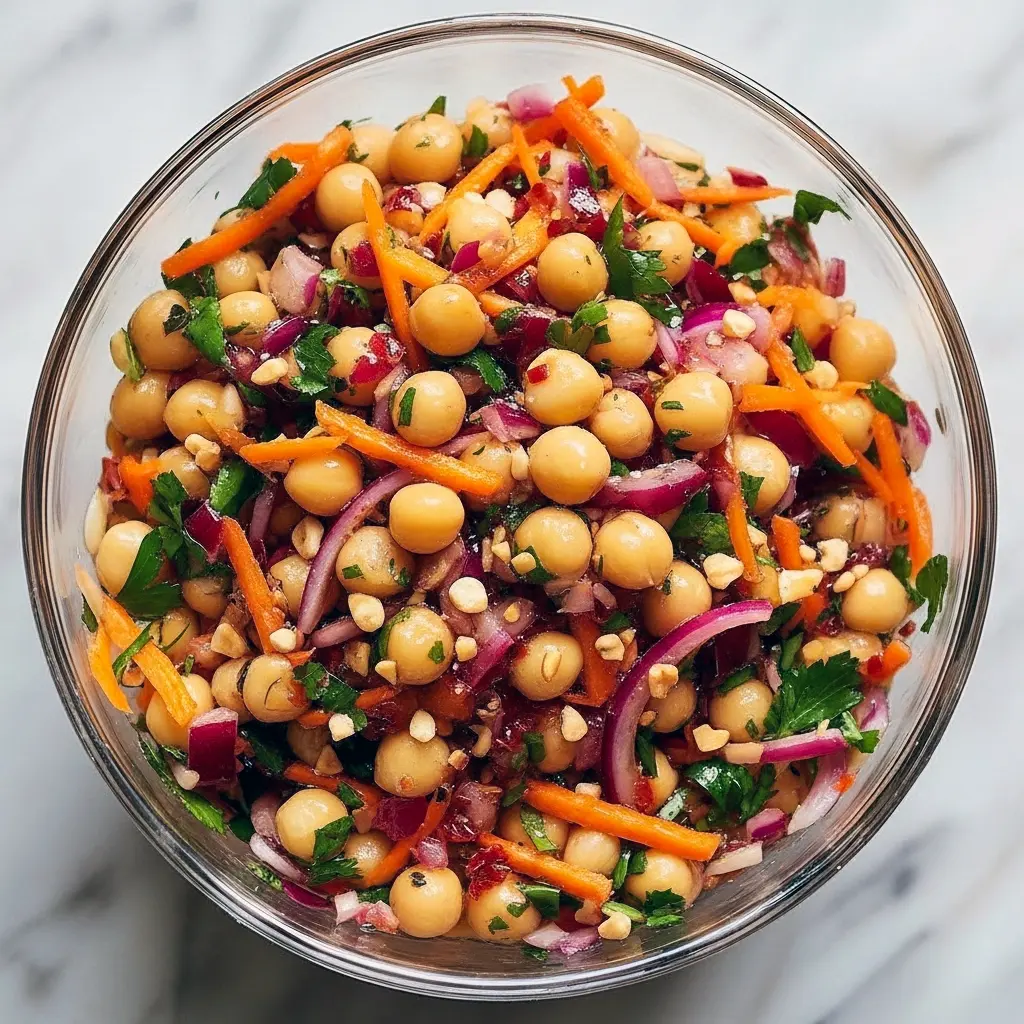 Bowl of Asian Chickpea Salad with shredded red cabbage, diced bell pepper, chickpeas, chopped peanuts, and a creamy tahini-lime dressing.