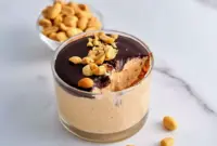 Jar of Cottage Cheese Peanut Butter Mousse drizzled with dark chocolate and chopped peanuts — a simple High Protein Desserts snack.