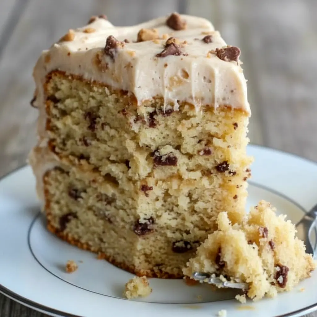 Banana Toffee Cake — slice showing banana-speckled crumb, glossy browned-butter toffee buttercream, and scattered toffee bits on top.