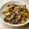 Garlic Mushroom Pasta in a shallow bowl: creamy sauce coating fettuccine, golden-browned mushrooms, grated Parmesan, and a sprinkle of parsley.