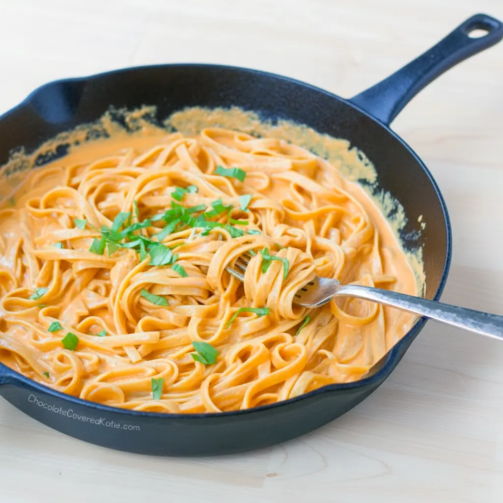 Plate of Red Pepper Alfredo Pasta — creamy red sauce coating fettuccine with a basil garnish, close-up overhead shot.
