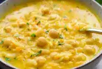 Bowl of Lemon Chickpea Orzo Soup with chickpeas, orzo, and a sprinkle of parsley in a golden, lemony broth.