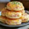 Golden Ham And Cheese Butter Swim Biscuits stacked on a plate, showing flaky layers, melted cheddar, and ham — ideal for Breakfast Brunch Recipes.