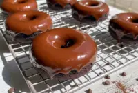 Chocolate Protein Donuts — six chocolate-glazed donuts on a wire rack, showing moist interior and glossy dark-chocolate finish, paleo and gluten-free.