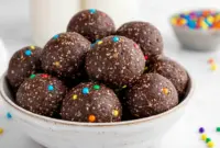 A plate of Cosmic Brownie Bites with a fudgy chocolate texture and rainbow candy-coated chips, styled as a healthy No Bake Dessert Bites treat.