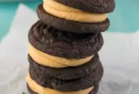 Stack of Homemade Peanut Butter Oreos showing soft chocolate sandwich cookies filled with creamy peanut butter frosting, styled like a rich homemade dessert.