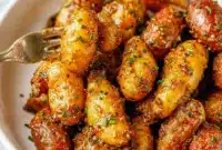 A skillet of Honey Mustard Potatoes with golden baby potatoes coated in a glossy honey mustard glaze and topped with fresh chives.