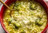 A bowl of Italian Broccoli Soup topped with parmesan cheese and olive oil, with tender broccoli, pasta, and garlic broth for a cozy homemade dinner.