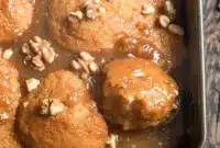 A spoonful of Maple Pudding Cake in a bowl, topped with glossy maple sauce and walnuts — a cozy Maple Syrup Pudding dessert close-up.