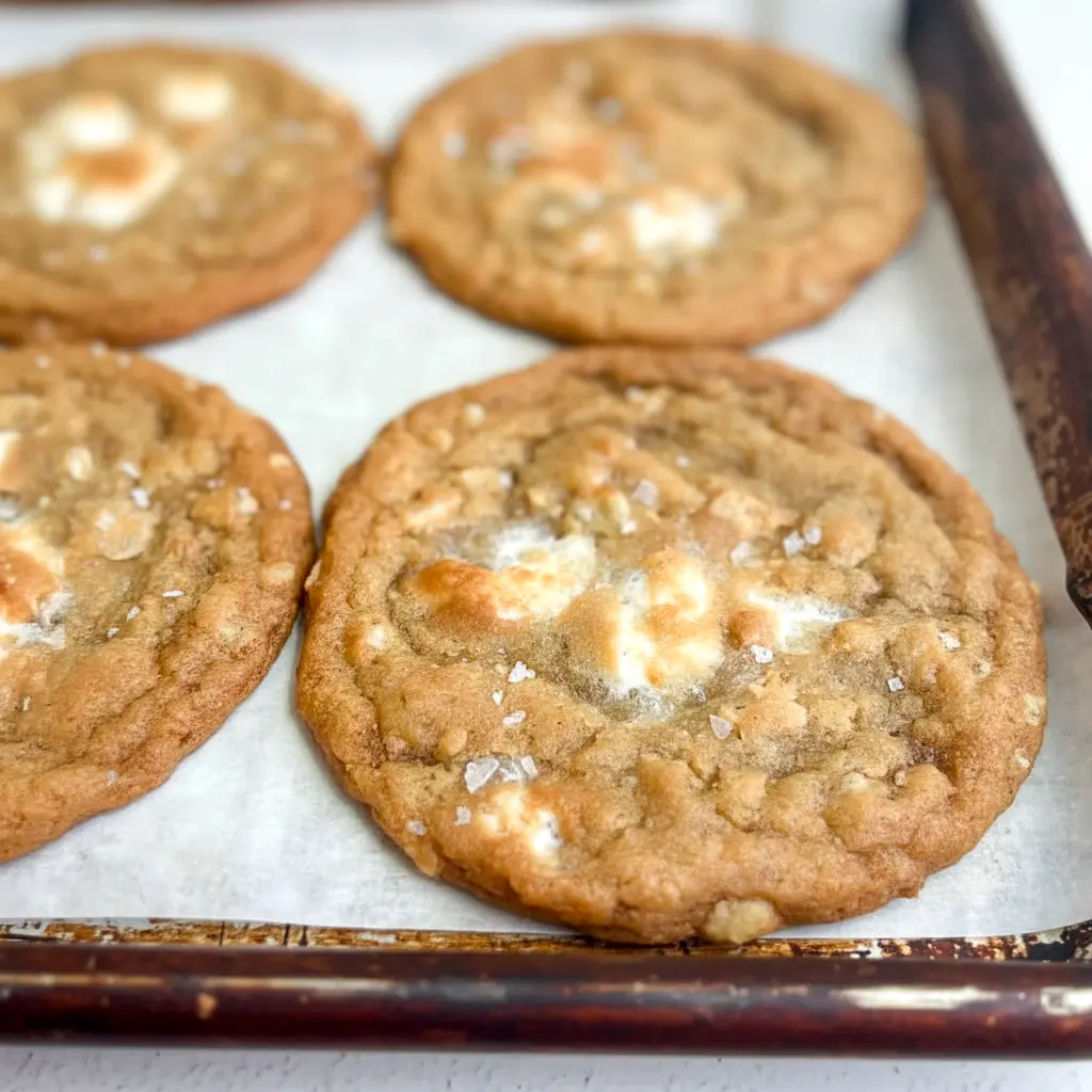 Plate of golden Marshmallow Crispy Cookies: thin, crispy edges with visible Rice Krispies and gooey marshmallow pockets, sprinkled with flaky salt.