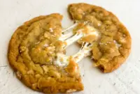 Plate of golden Marshmallow Crispy Cookies: thin, crispy edges with visible Rice Krispies and gooey marshmallow pockets, sprinkled with flaky salt.