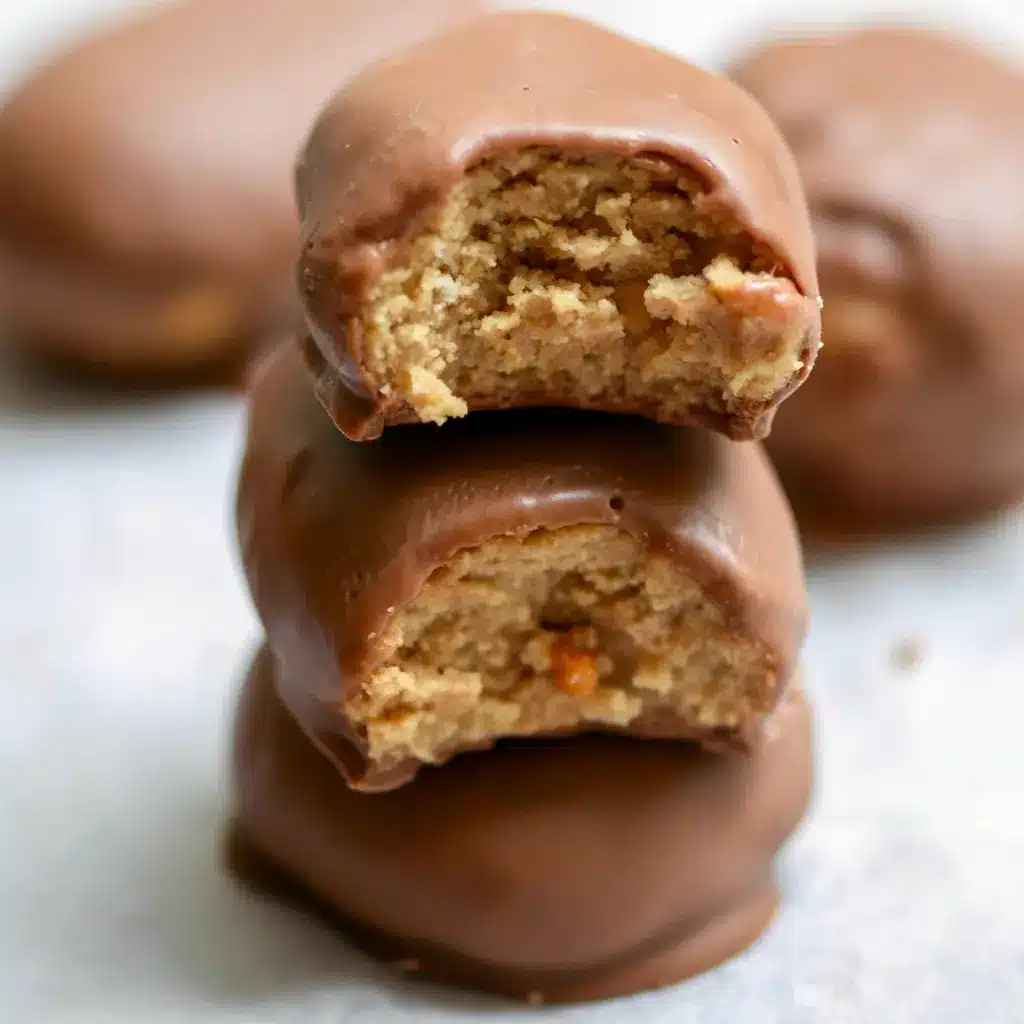 Close-up of Peanut Butter Protein Bars dipped in chocolate and cooling on parchment paper — chewy, chocolate-coated snack ready to eat.