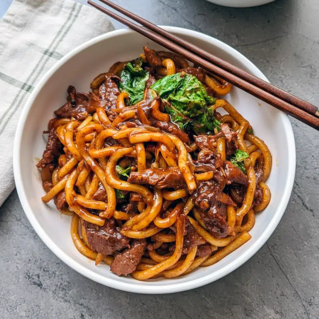 Bowl of Beef Udon with sliced steak, Chinese cabbage, and glossy black-pepper sauce over springy Noodles.
