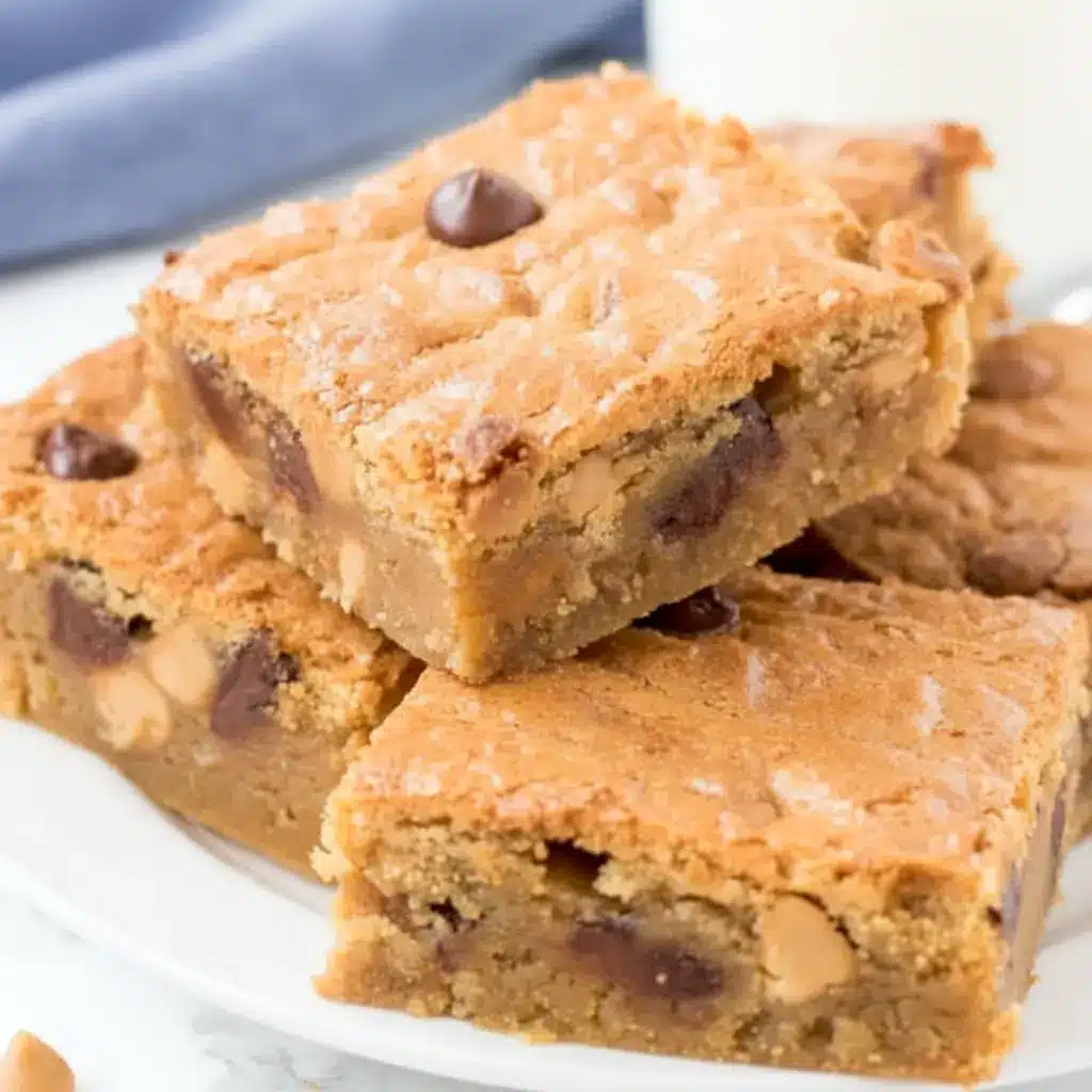 Thick square Peanut Butter Blondies cut on a serving board, styled as a gooey Peanut Butter Blondie dessert with a dense, fudgy texture and colorful Reese’s Pieces.
