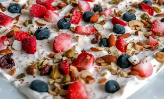 A sheet of Frozen Yogurt Bark topped with berries and nuts for a refreshing, crunchy, and colorful dessert.