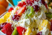 A bowl of Hawaiian Cheesecake Salad with pineapple, strawberries, kiwi, raspberries, and toasted coconut in a creamy cheesecake filling.