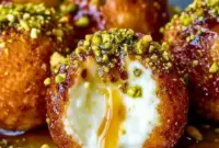 A platter of Ricotta Pistachio Honey Bites topped with chopped pistachios and honey drizzle, styled as a creamy, elegant appetizer for New Years Foods.