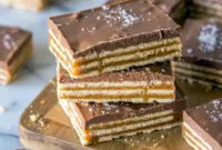 Salt River Bars stacked on a dessert tray for a rich Salt River Bars Recipe with caramel, chocolate, and flaky sea salt.
