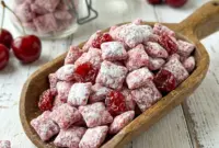 A sweet bowl of Cherry Cheesecake Puppy Chow finished with powdered sugar and cherries, perfect for Snack Exchange Ideas.